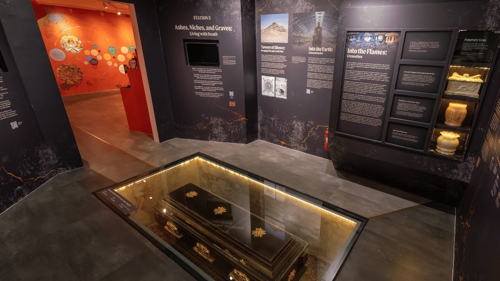 Exhibit at Hell's Museum showing a coffin beneath a glass floor, illustrating burial practices.