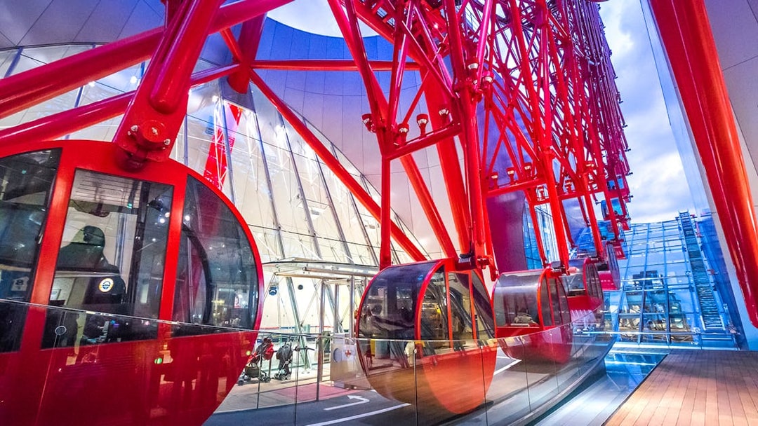 Red gondolas of the HEP Ferris Wheel in a modern glass building.