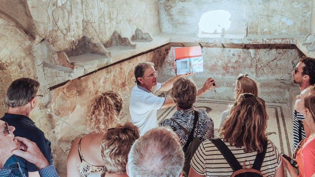 Group listening to archaeologist during Herculaneum tour inside ancient ruins.