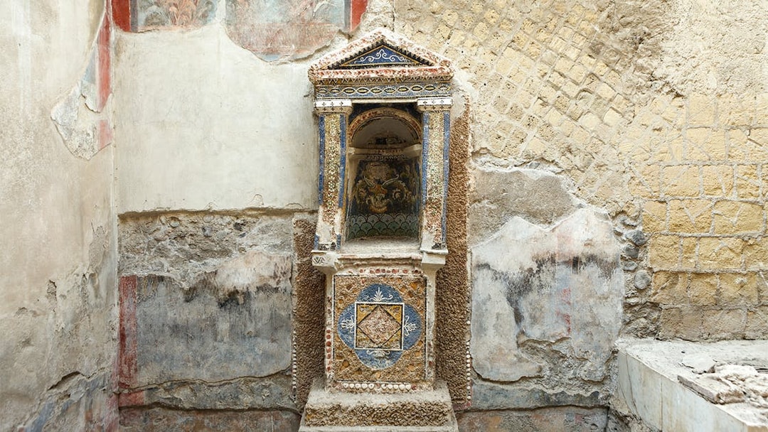 Ancient frescoed niche in Herculaneum with intricate mosaic details.