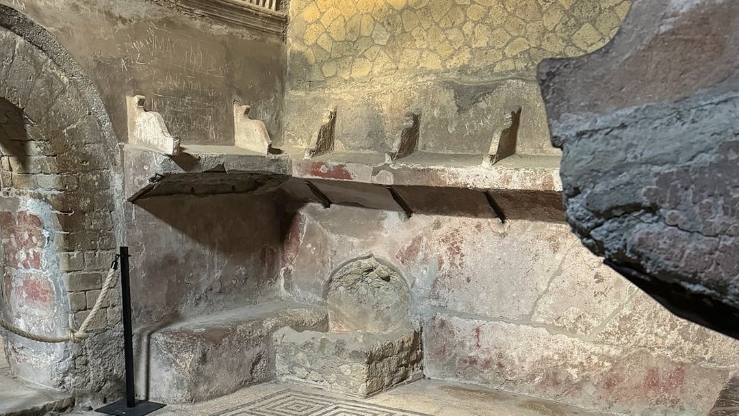 Herculaneum Ruins ancient bathhouse interior with stone seating and mosaic floor.