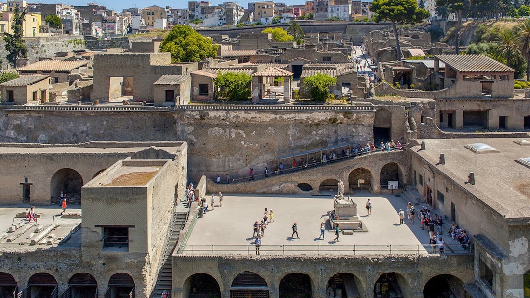 Visitors walking through the ancient ruins of Herculaneum basilica site.