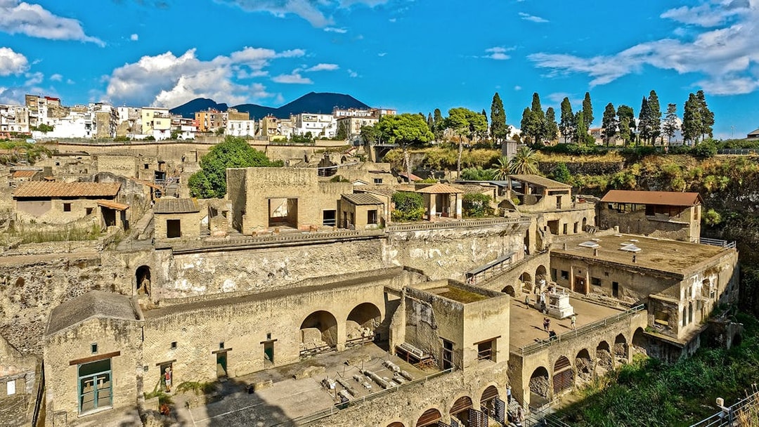 Panoramic view of ancient ruins in Herculaneum, Italy, with Mount Vesuvius in the background.