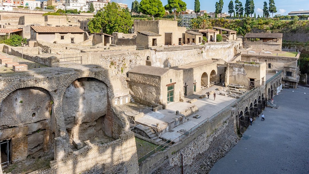 Ruins of Herculaneum entrance with ancient stone structures and arches, Italy.