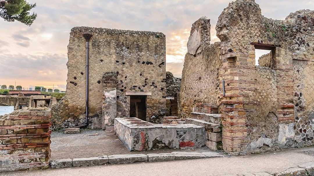 Ancient thermopolium ruins in Herculaneum with stone counters and walls.