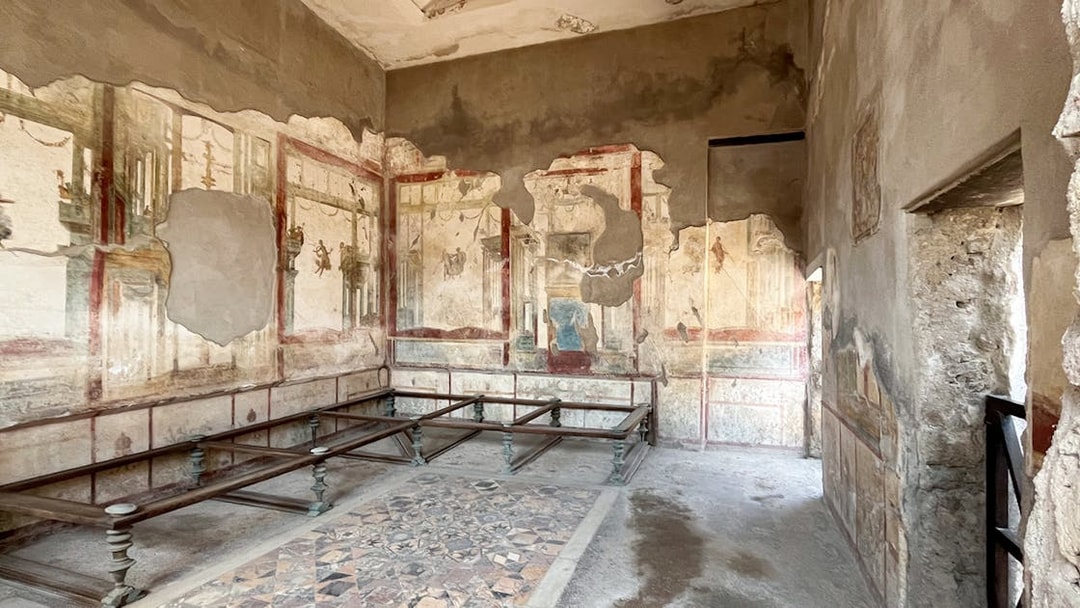 Herculaneum Ruins interior with ancient frescoes and stone benches.