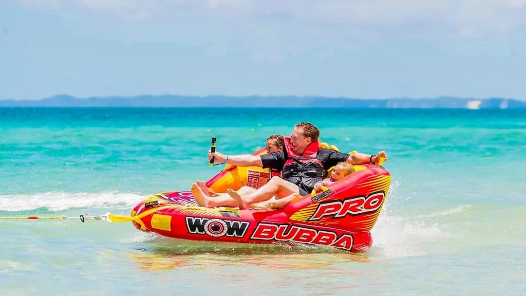 Tourists enjoying watersports on an inflatable raft at Fraser Island, K'gari.