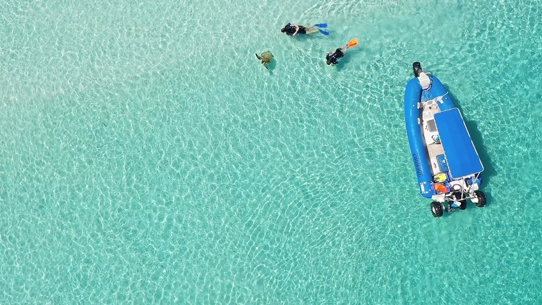 Snorkelers and a boat in clear waters during a K'gari (Fraser Island) tour.