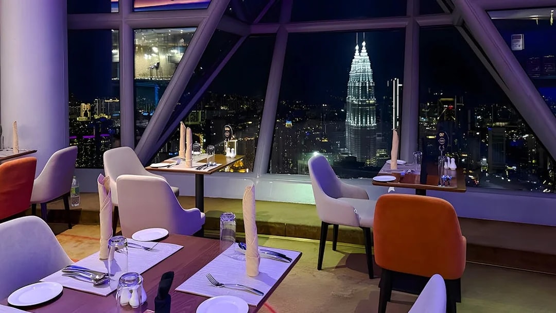 Dining tables with a view of Kuala Lumpur skyline from Orbit Revolving Restaurant in KL Tower.
