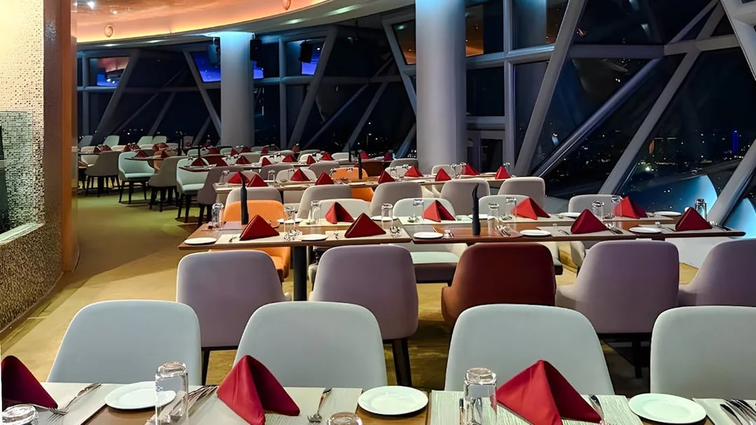 Dining setup at Orbit Revolving Restaurant, KL Tower, Kuala Lumpur, with city skyline view.