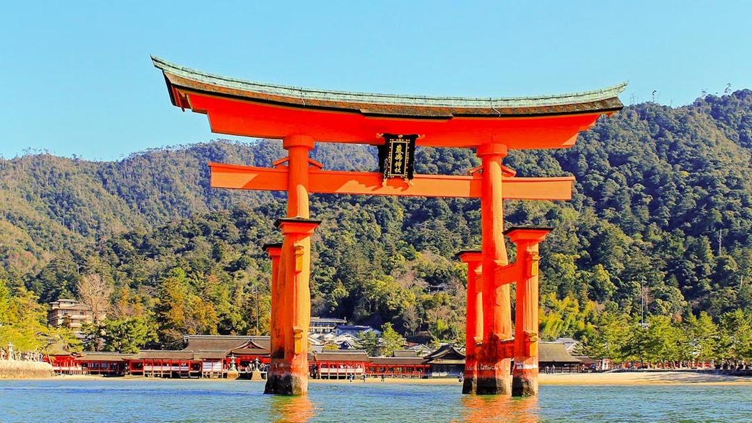 Otorii Gate at Itsukushima Shrine, Miyajima Island, Japan, with forested hills in the background.