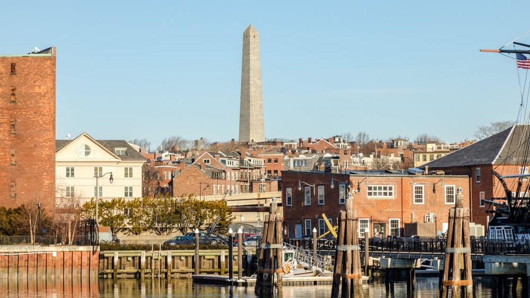 Bunker Hill Monument viewed from the harbor with historic brick buildings in Boston.