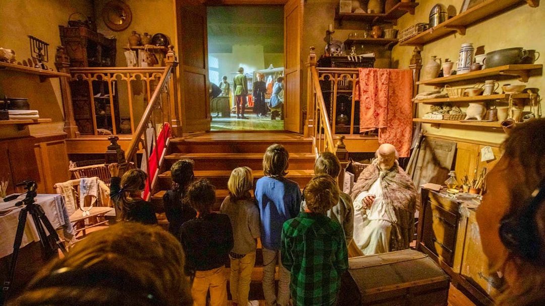 Guests watching a historical reenactment at Historium Bruges, featuring medieval decor and artifacts.
