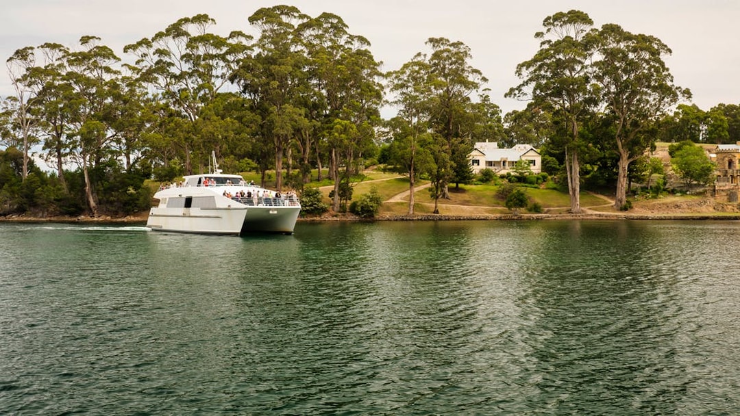 Ferry approaching Port Arthur Historic Site, Tasmania, surrounded by trees and water.