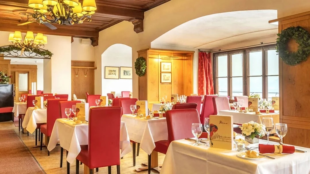 Dinner setup in Fortress Hohensalzburg dining room with red chairs and white tablecloths.