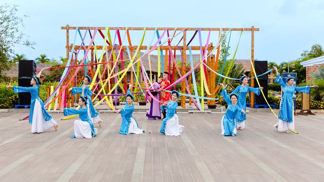 Performers in traditional costumes at Hoi An Memories Show, Vietnam, with colorful ribbons.