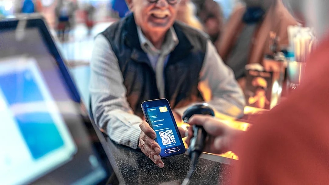 Scanning a digital voucher with a QR code at a ticket counter.
