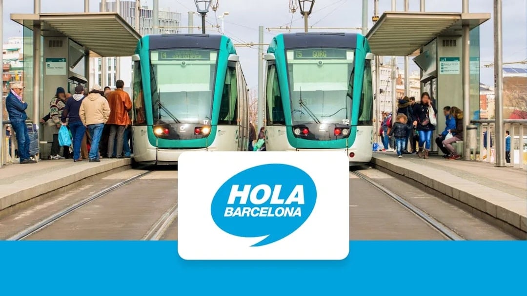 Trams at a Barcelona station with passengers boarding, Hola Barcelona logo displayed.