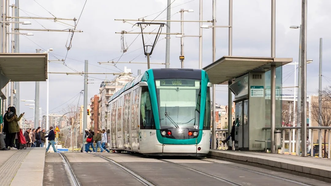 Tram at a Barcelona station with passengers boarding, part of the Hola Barcelona tour.