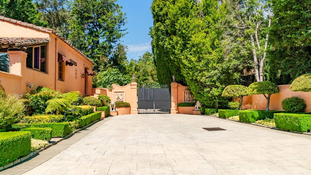 Beverly Hills mansion entrance with manicured hedges and iron gate, known as "The Godfather House.