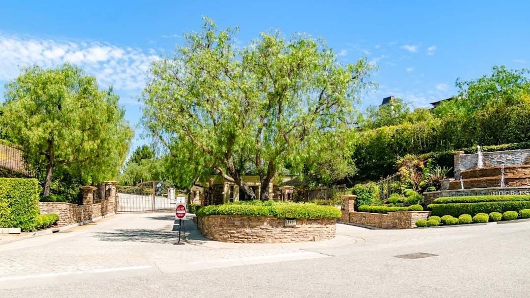 Gated entrance to a celebrity home in Los Angeles surrounded by lush greenery.