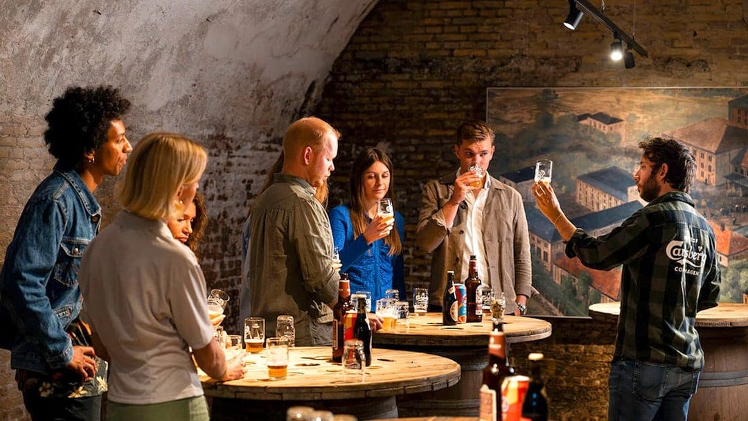 Guests participating in a beer tasting session in a rustic cellar setting.