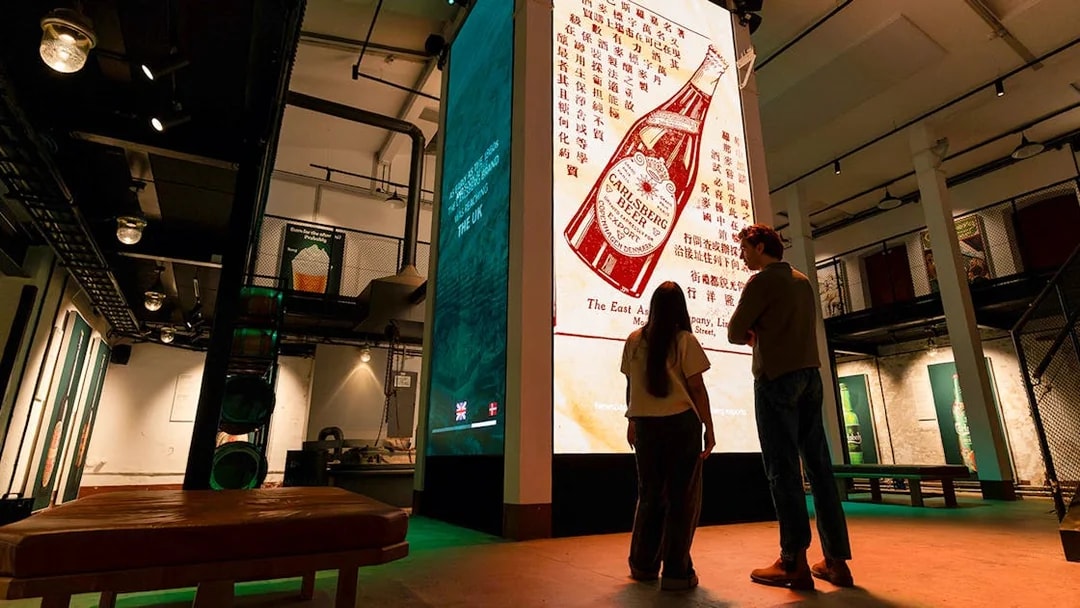 Visitors viewing Carlsberg beer exhibit inside Home of Carlsberg museum.