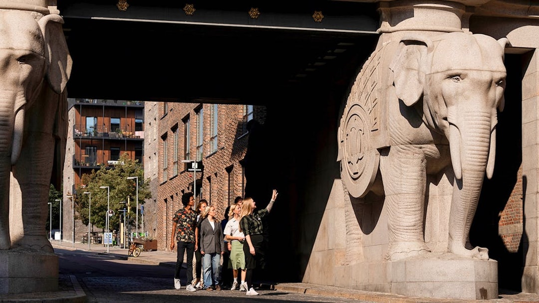 Guests observing elephant sculptures at the entrance of the Carlsberg brewery in Copenhagen.