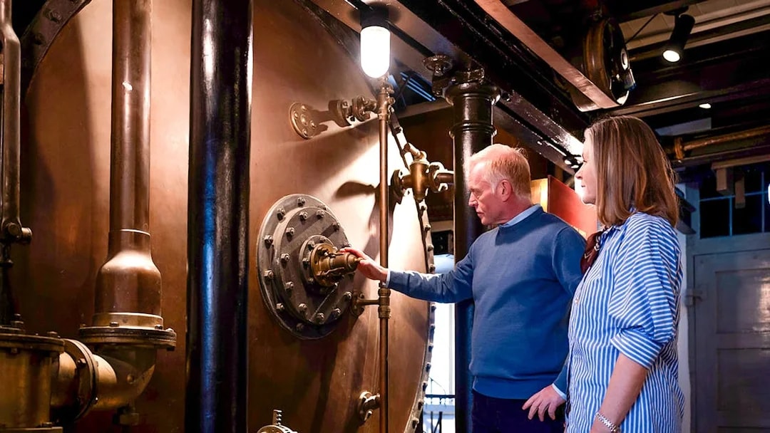 Guests examining brewing equipment in a brewery tour.