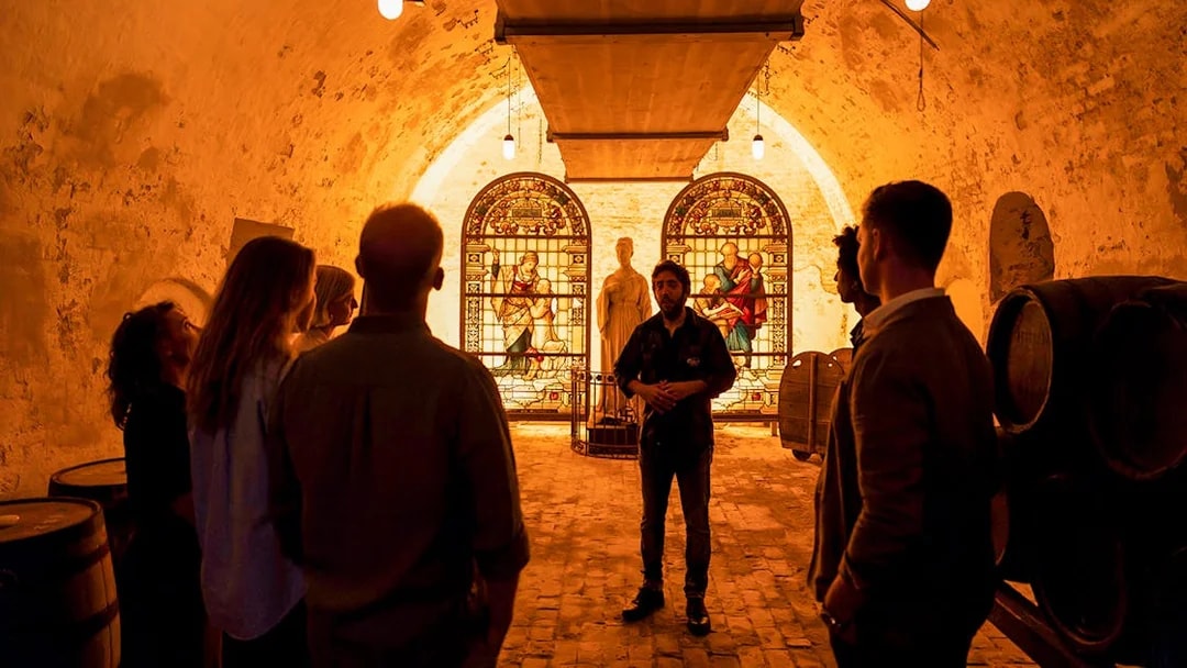 Tour group inside Carlsberg cellar with stained glass and statue exhibit.