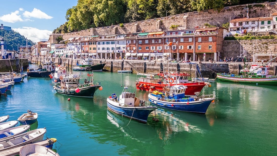Colorful fishing boats docked in Hondarribia harbor, Spain, with historic buildings in the background.