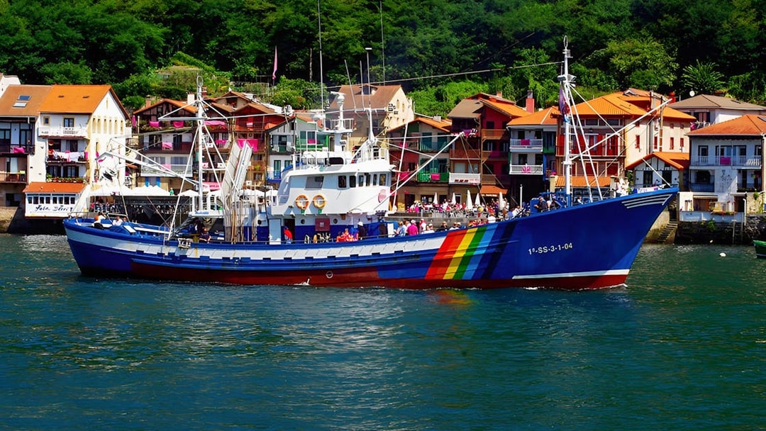 Colorful fishing boat in Hondarribia harbor with vibrant houses in the background.