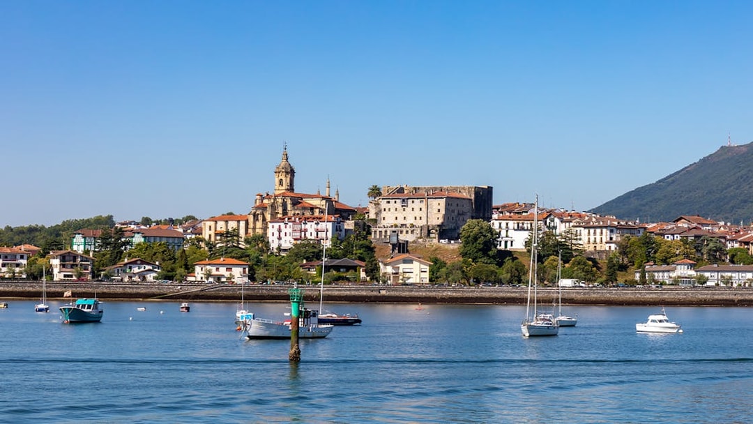 Hondarribia waterfront with boats and historic buildings under a clear blue sky.