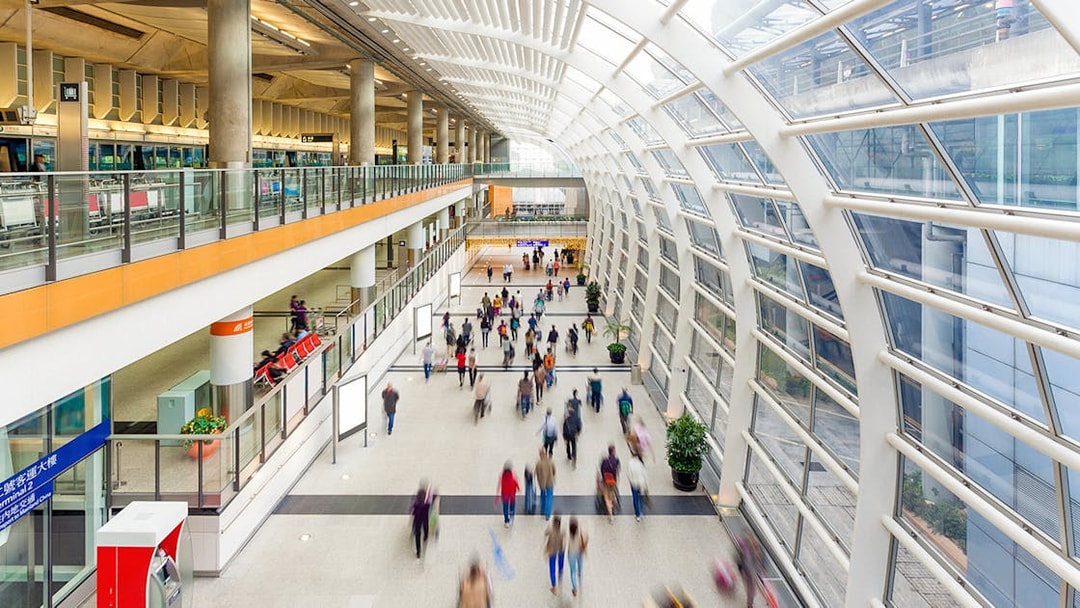 Passengers walking in Hong Kong airport terminal for express transfers.