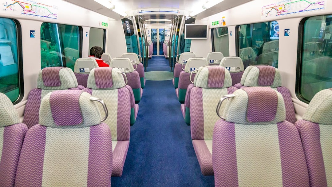 Interior of Hong Kong Airport Express train with empty seats and passenger.