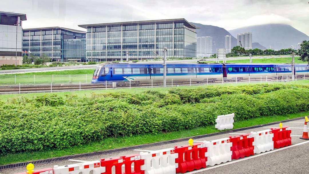 Train traveling between Hong Kong International Airport and city with modern buildings in background.