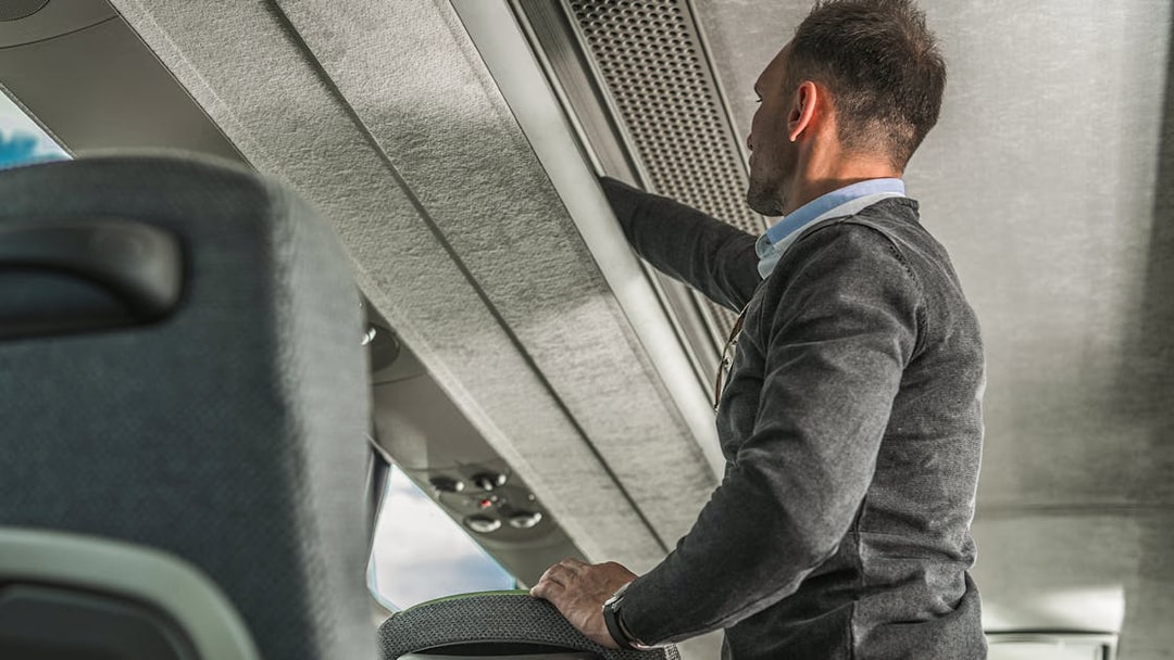 Passenger using overhead luggage storage on Hong Kong Airport Express.