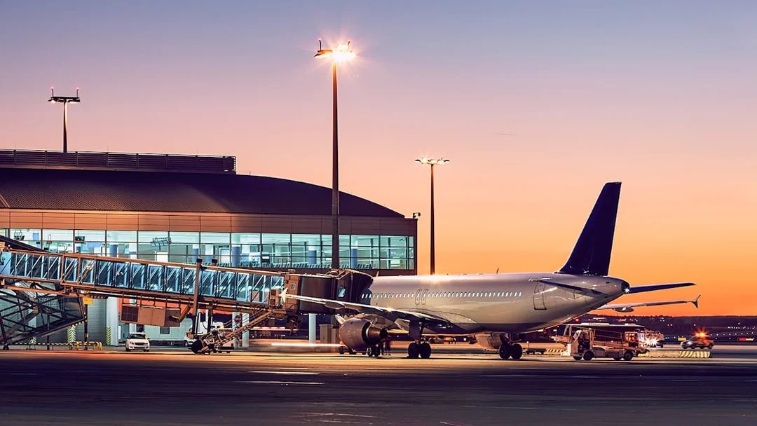 Airplane at London City Airport gate during sunset.