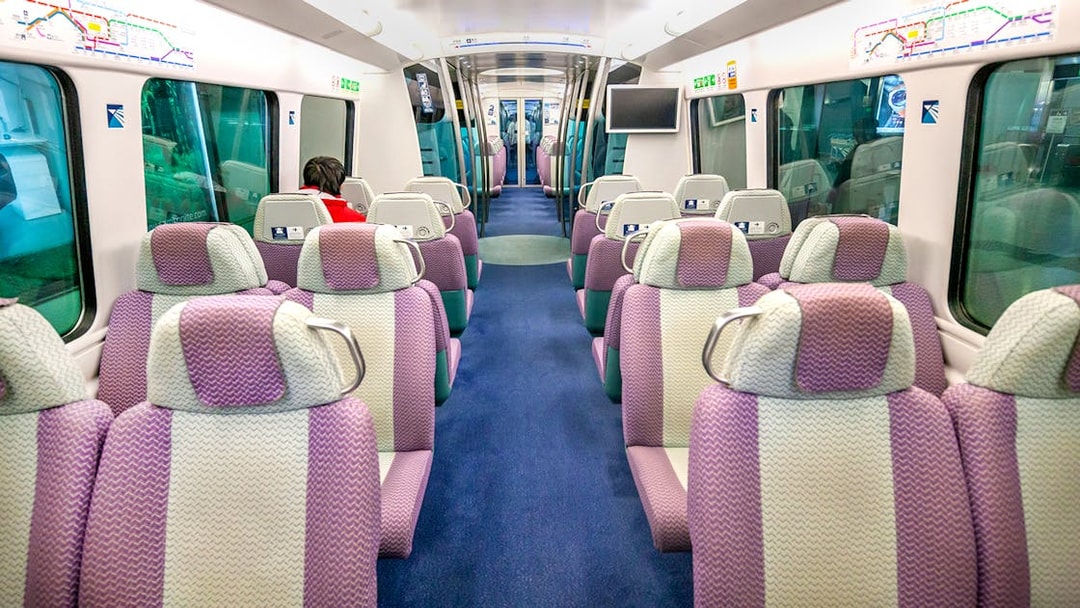 Interior of Hong Kong Airport Express train with purple seats and passenger.
