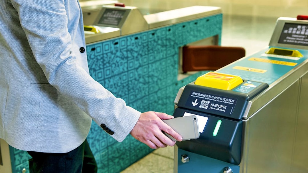Person scanning phone at Hong Kong Airport Express turnstile.