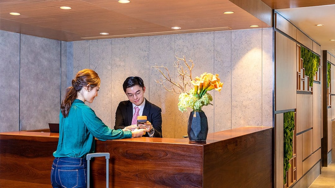 Receptionist assisting traveler at Plaza Premium Lounge check-in counter.