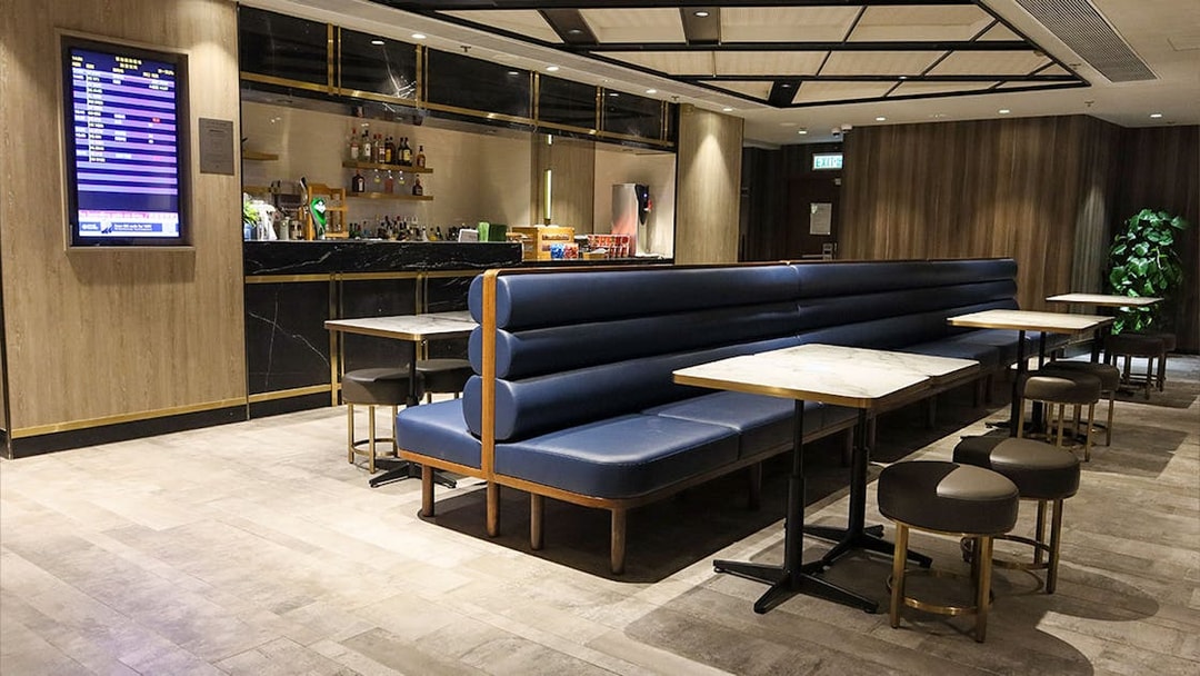 Plaza Premium Lounge seating area with bar and flight information display.