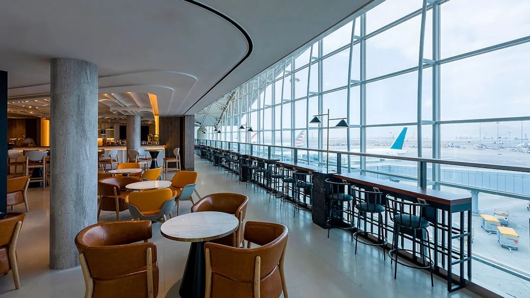 Plaza Premium Lounge with seating and airport runway view through large windows.