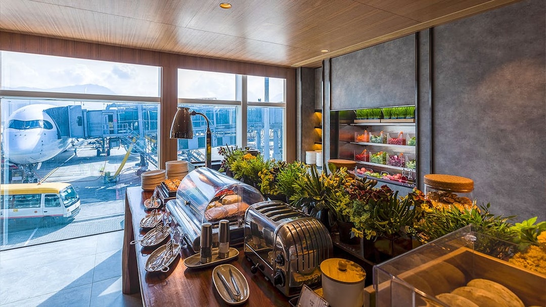 Plaza Premium Lounge buffet with view of airplane at airport terminal.