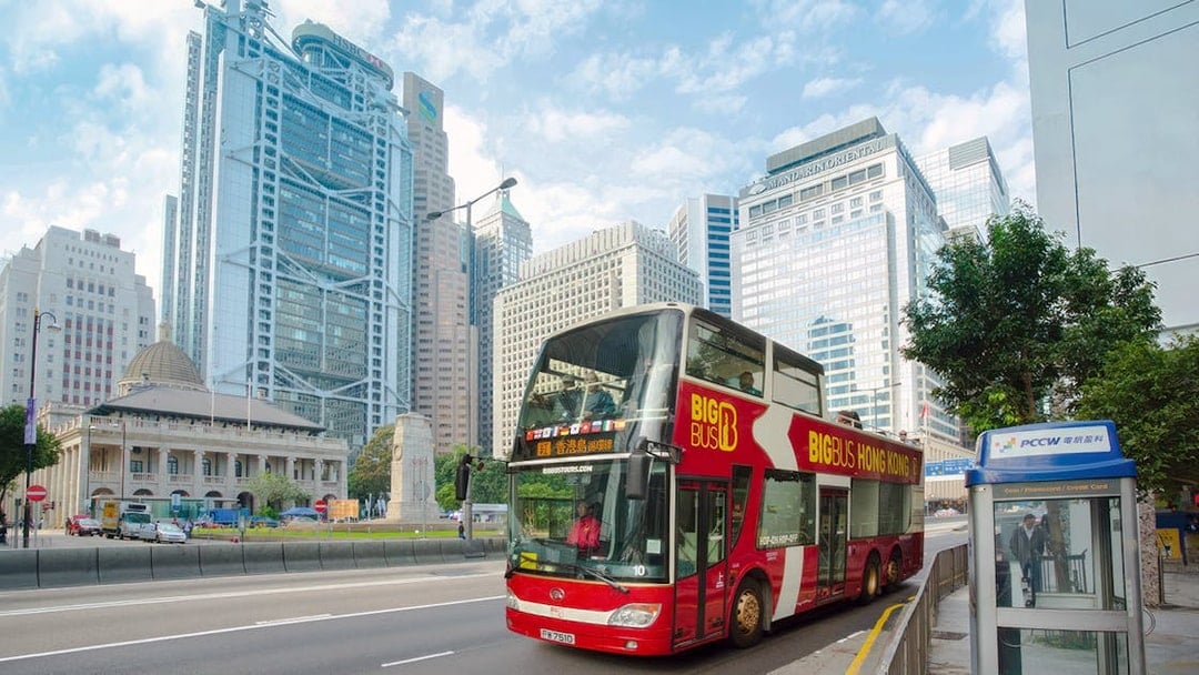 Big Bus tour in Hong Kong passing modern skyscrapers.