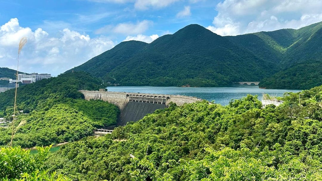 Scenic view of lush green hills and a dam near a lake on the Big Bus Hop-On Hop-Off Tour.