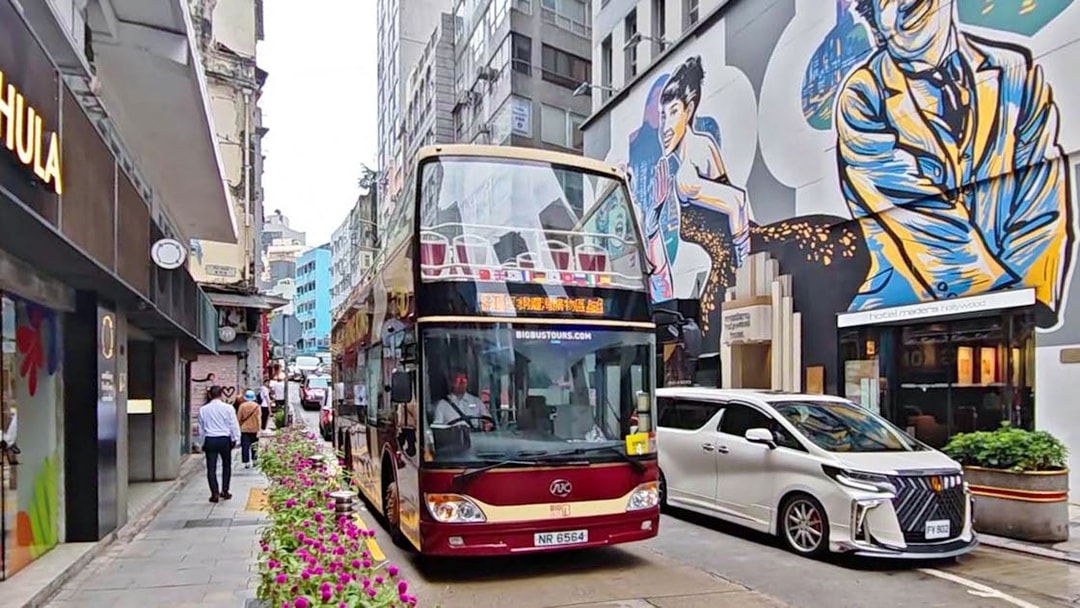 Double-decker bus on Hong Kong street with colorful mural, part of Big Bus Tour.