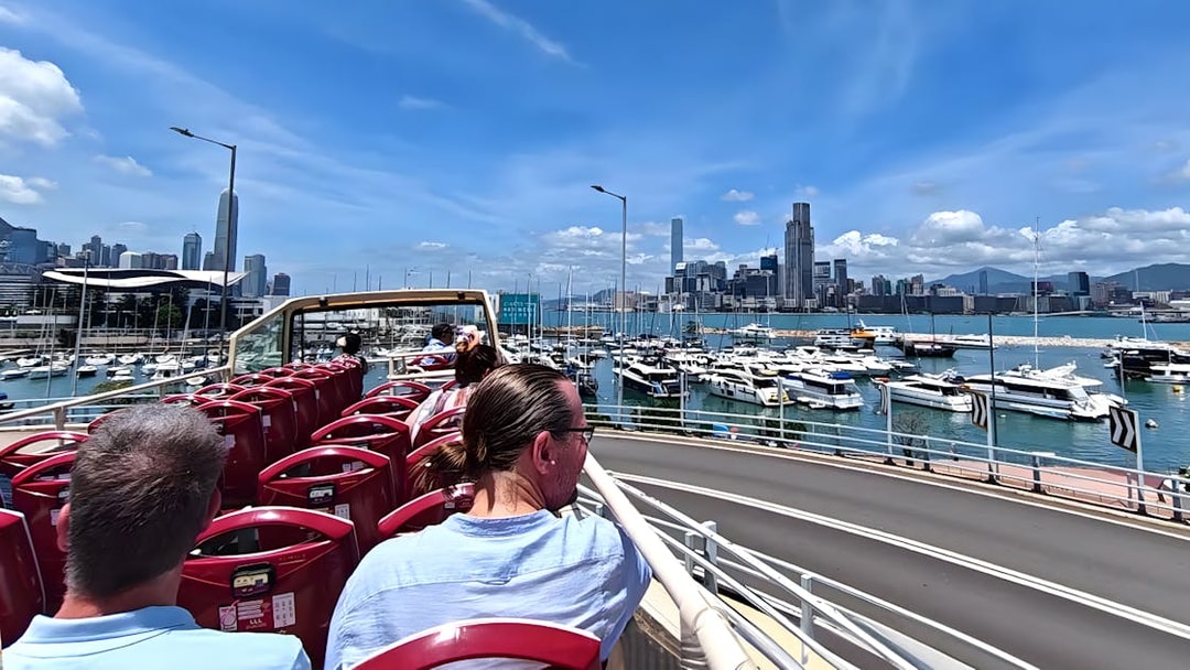 Guests on an open-top bus tour in Hong Kong with a view of the skyline and harbor.