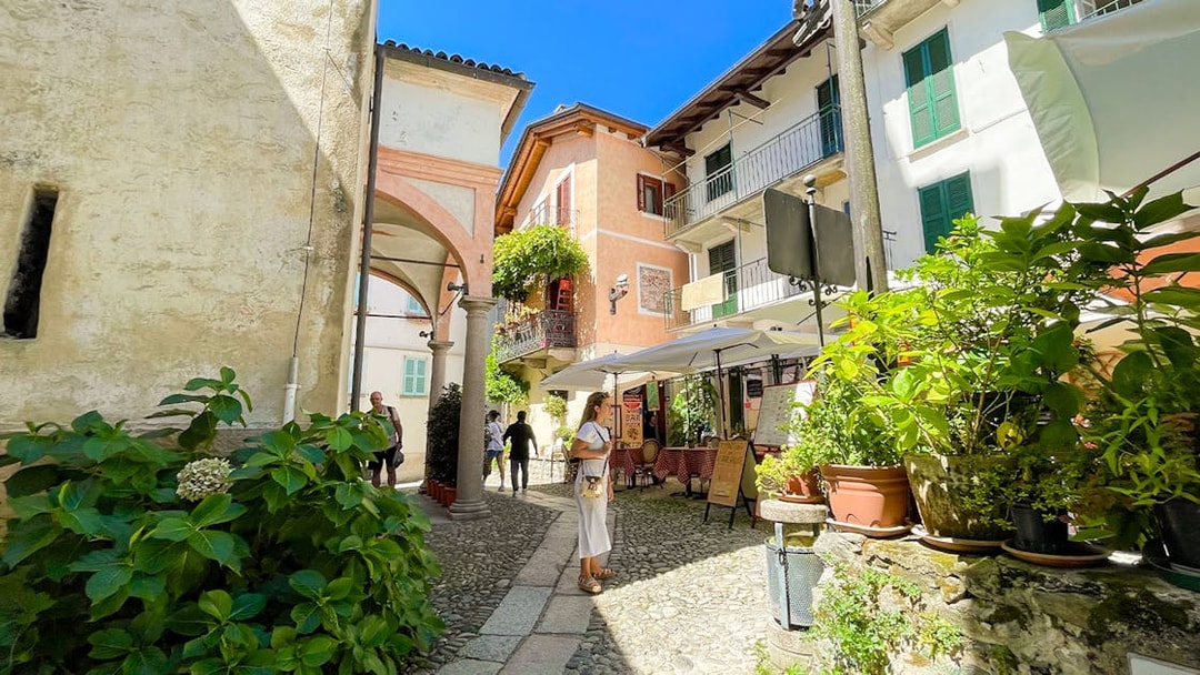 Cobblestone street with tourists and cafes in Isole Borromee, Italy.