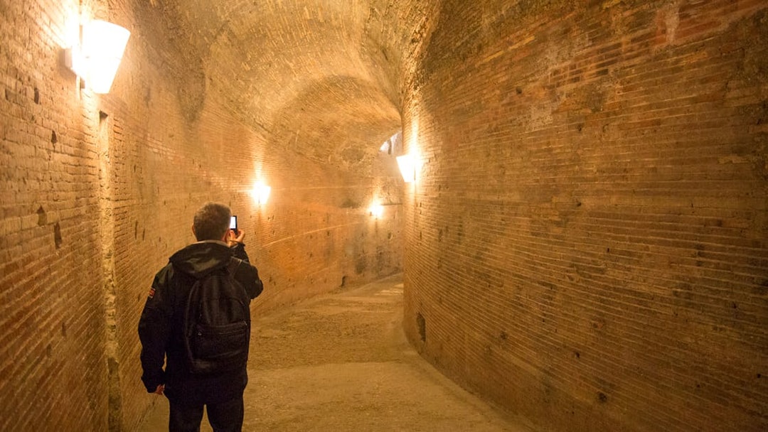 Visitor exploring a brick corridor inside Castel Sant'Angelo, Rome.